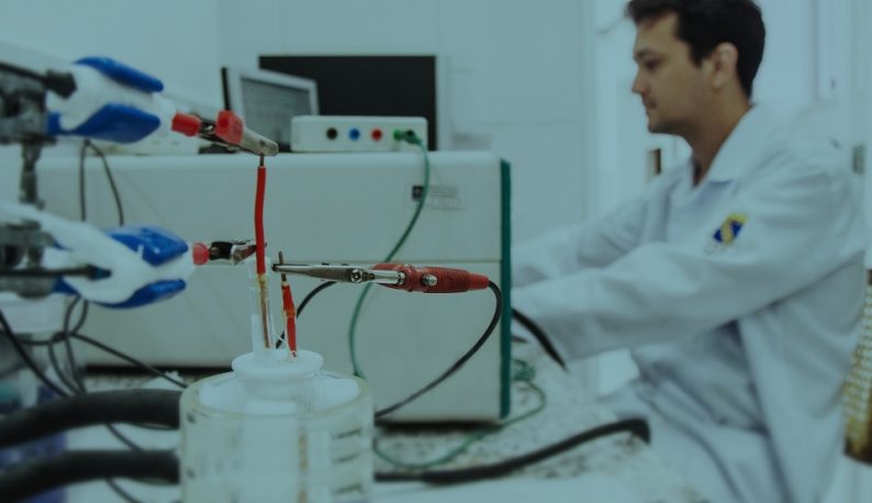 Equipamentos de eletroquímica aplicados em amostra líquida, com pesquisador ao fundo (Foto: Ribamar Neto/UFC)