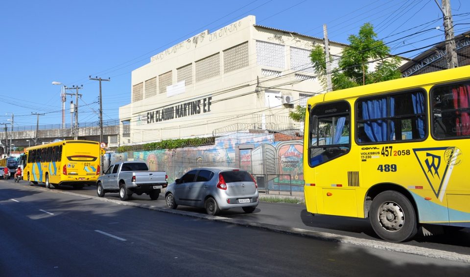 Ônibus, carros e motocicletas passando em uma avenida, em frente a uma escola de ensino fundamental (Foto: Prof. Ivan Ary Júnior/UFC)