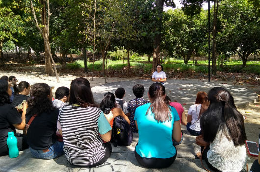 Pessoas sentadas no anfiteatro do parque, acompanhando a explicação da coordenadora do projeto (Foto: Luana Oliveira/PREX-UFC)