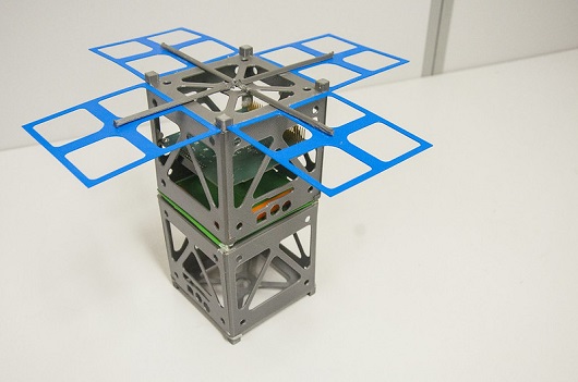 Modelo do nanossatélite, composto por dois cubos de 10 centímetros cúbicos e espaço para painéis solares, colocado sobre uma mesa (Foto: Ribamar Neto/UFC)