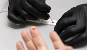 Dedo furado e sangue sendo usado em equipamento de testagem