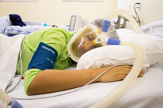 Paciente deitada de bruços na maca, usando a máscara de respiração