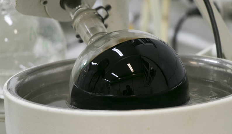 Recipiente transparente e redondo, em laboratório, com líquido preto dentro