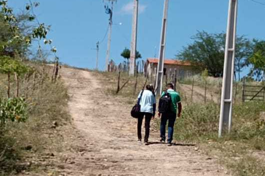 Dois pesquisadores caminham por estrada de terra no interior do município de Barro
