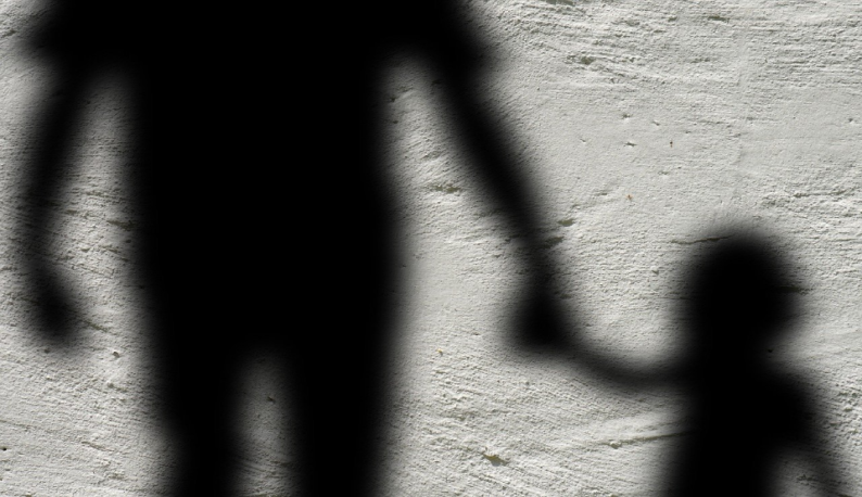 Imagem da sombra de um adulto segurando a mão de uma criança