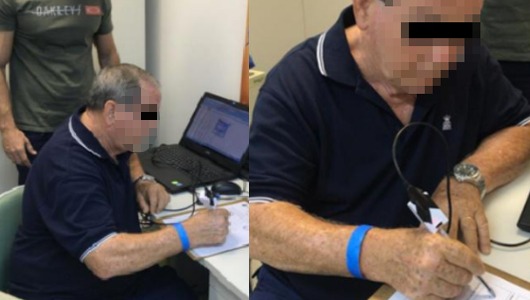 Imagem: idoso sentado a uma mesa, escrevendo com a caneta inteligente num teste de identificação de Parkinson