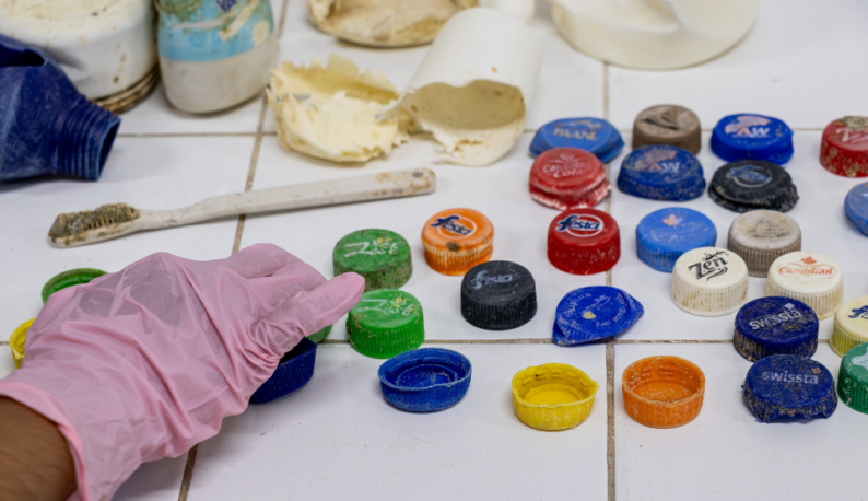 Imagem de tampas de garrafa e outros itens plásticos organizados sobre uma mesa