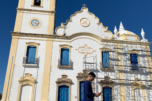 Jovem em frente a uma igreja histórica segurando equipamento de análise