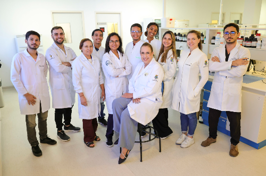 Pesquisadores de jaleco posam para foto no laboratório