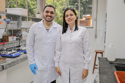 Dois pesquisadores de jaleco no laboratório