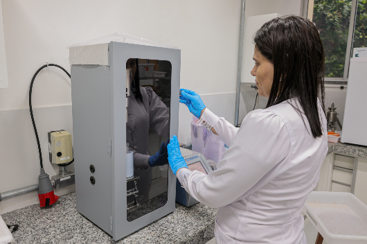 Pesquisadora manuseia equipamento em laboratório