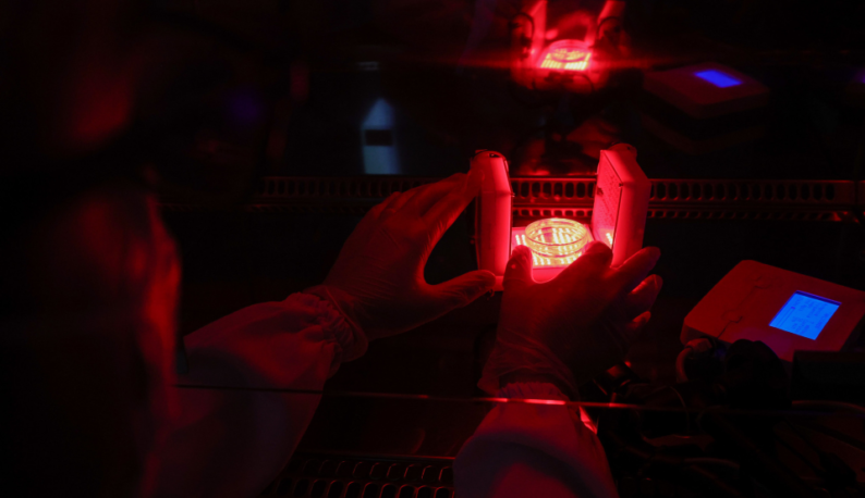 Imagem de pesquisador manejando experimento sob luz vermelha