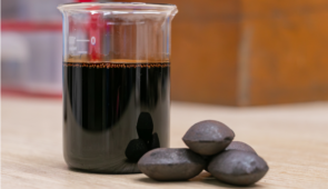 Imagem de líquido da castanha de caju em um recipiente e, ao lado, briquetes feitos com LCC