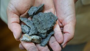 Fotografia em close de duas mãos segurando minério de grafita (Foto: Ribamar Neto/UFC)