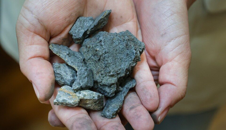 Fotografia em close de duas mãos segurando minério de grafita (Foto: Ribamar Neto/UFC)