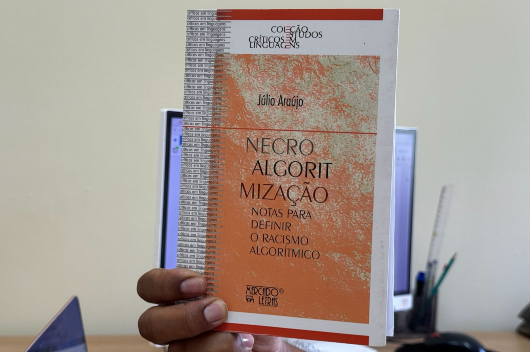 Imagem de um livro sendo segurado por uma mão, com destaque para sua capa