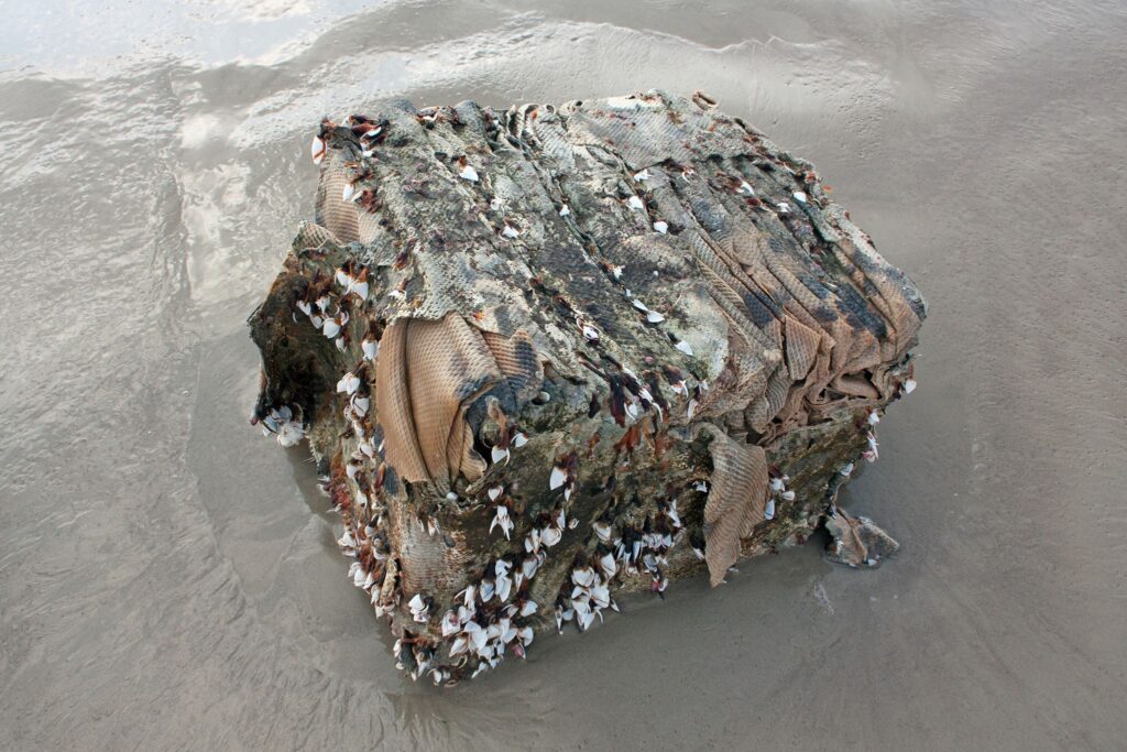 Imagem de um fardo de borracha na areia da praia