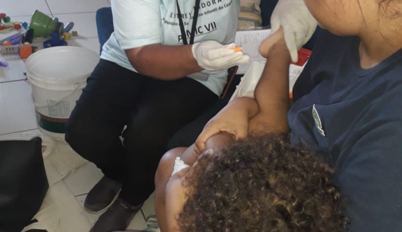 Profissional fazendo coleta de sangue no pé de uma criança