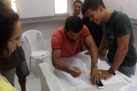 Pesquisador e pescadores desenham mapas em uma mesa