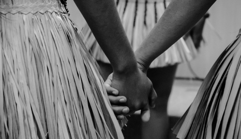 Fotografia de duas pessoas indígenas segurando as mãos