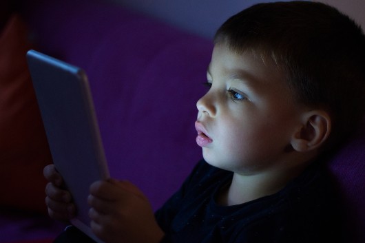 Fotografia de criança utilizando um tablet à noite